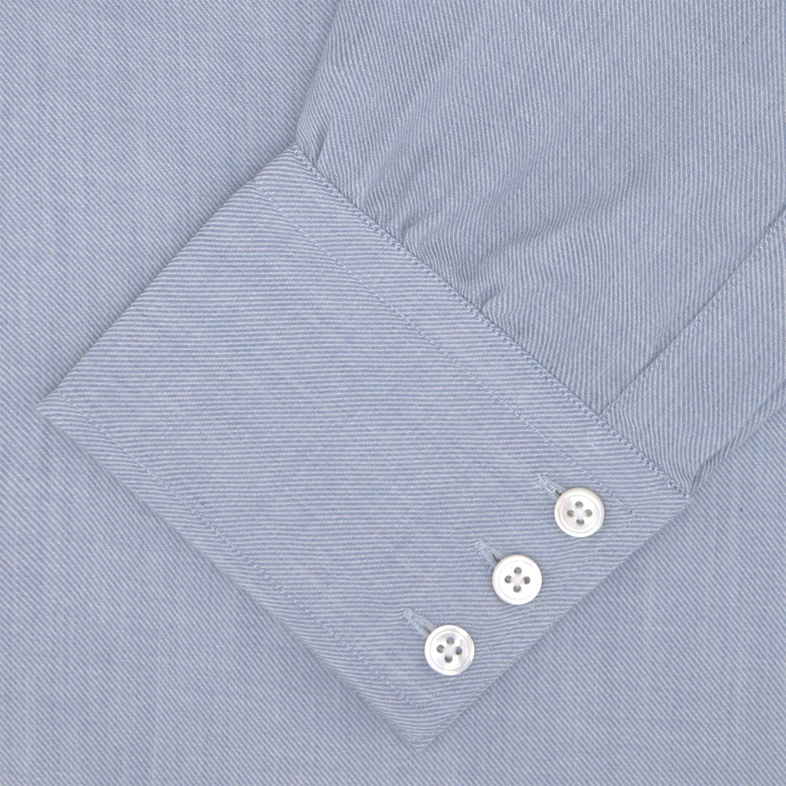 View 4 of product The Turnbull & Asser Blue Cashmere Blend Shirt features a T&A collar and 3-button cuffs, elegantly folded and showcased against a plain white background.