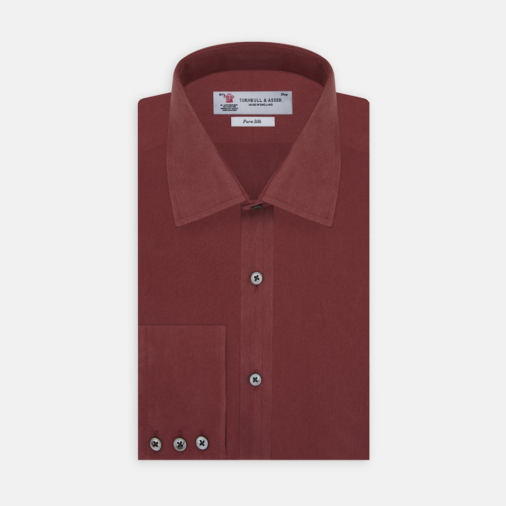 The Turnbull & Asser Burgundy Silk Shirt features a T&A collar and 3-button cuffs, offering a refined alternative to a black tie for modern style. Displayed folded on a white background.