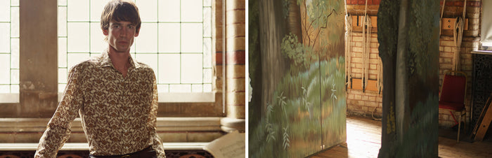 A man in a patterned shirt stands by a large window in a room with brick walls; next to him, a view of a painted wall and a red chair in a similarly lit, rustic interior.