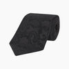 View 1 of product The Black Paisley Silk Tie by Turnbull & Asser features an elegant swirling paisley design with a subtle sheen—an all-black statement accessory photographed rolled up on a white background.