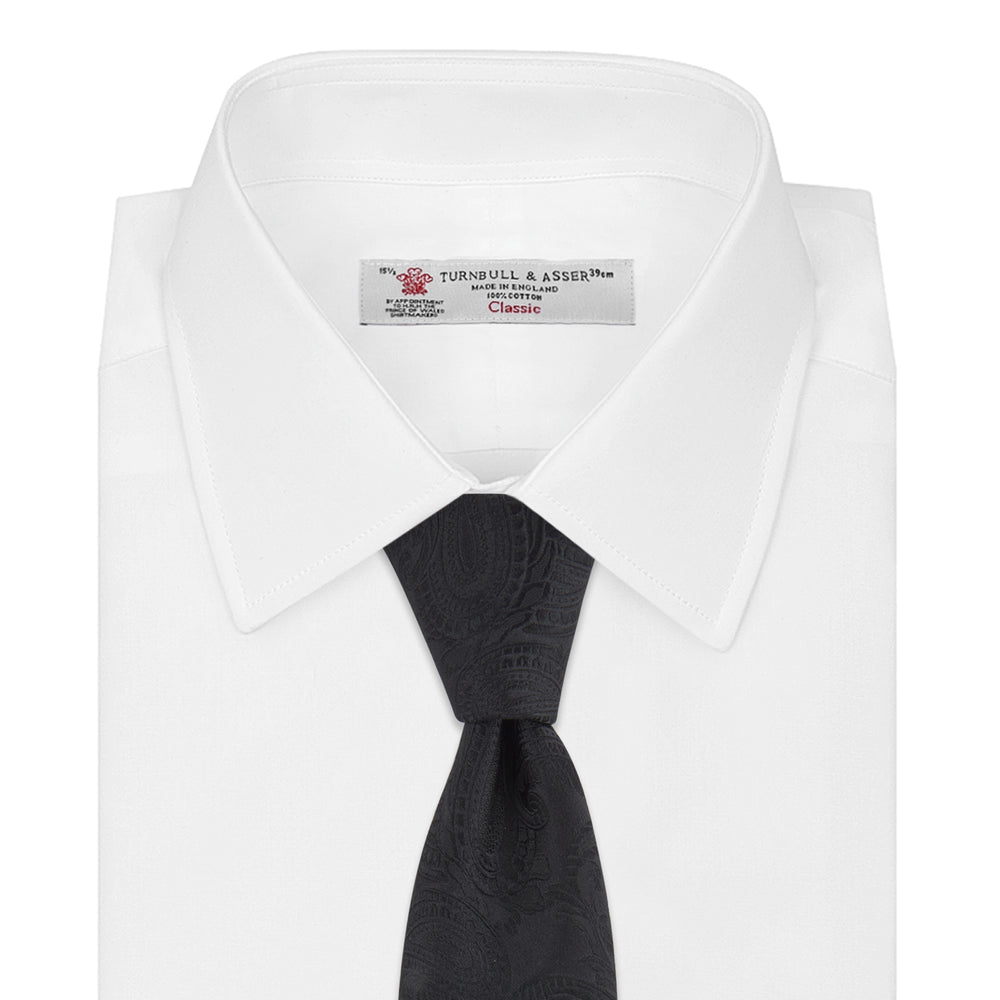 The Black Paisley Silk Tie by Turnbull & Asser features an elegant swirling paisley design with a subtle sheen—an all-black statement accessory photographed rolled up on a white background.