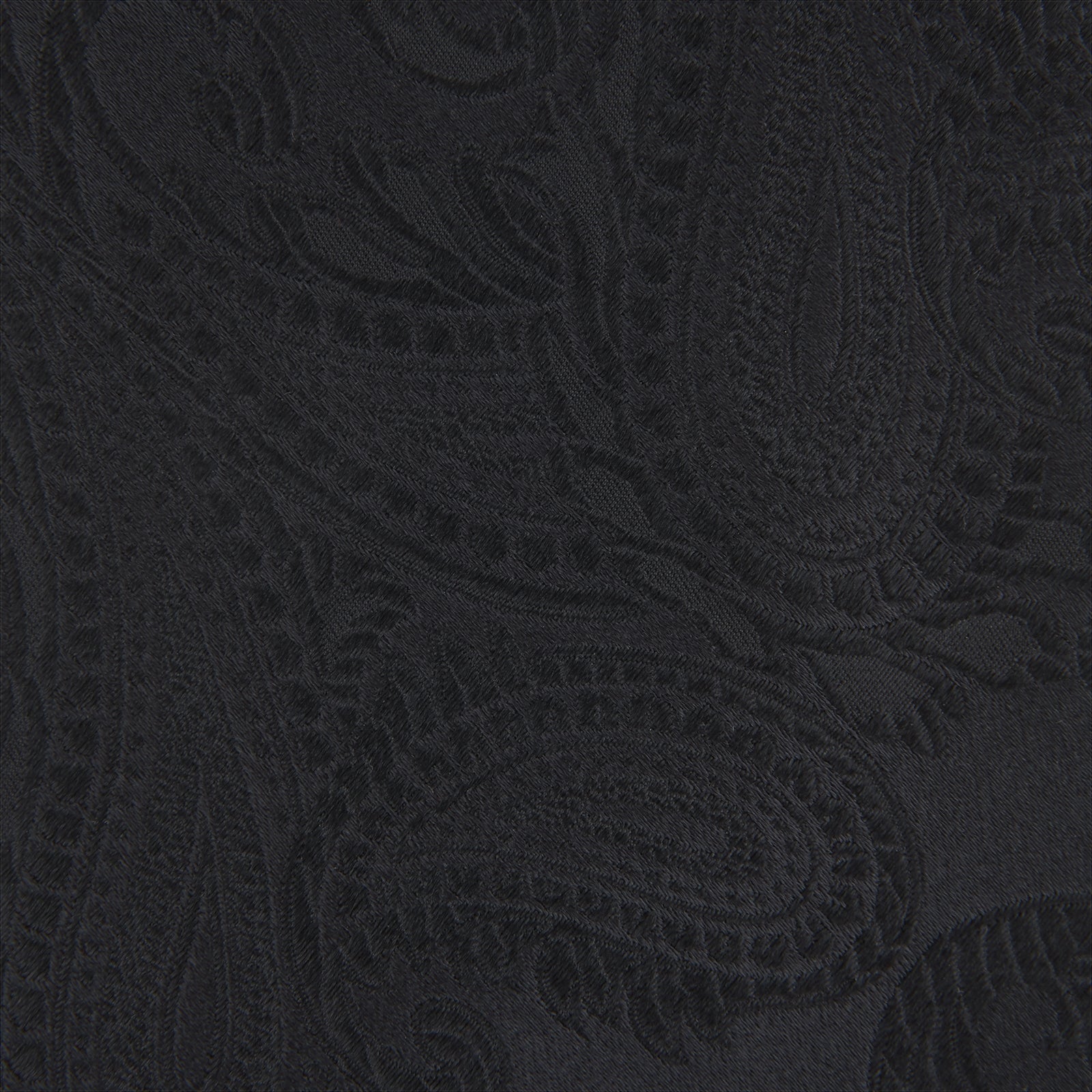 View 3 of product The Black Paisley Silk Tie by Turnbull & Asser features an elegant swirling paisley design with a subtle sheen—an all-black statement accessory photographed rolled up on a white background.