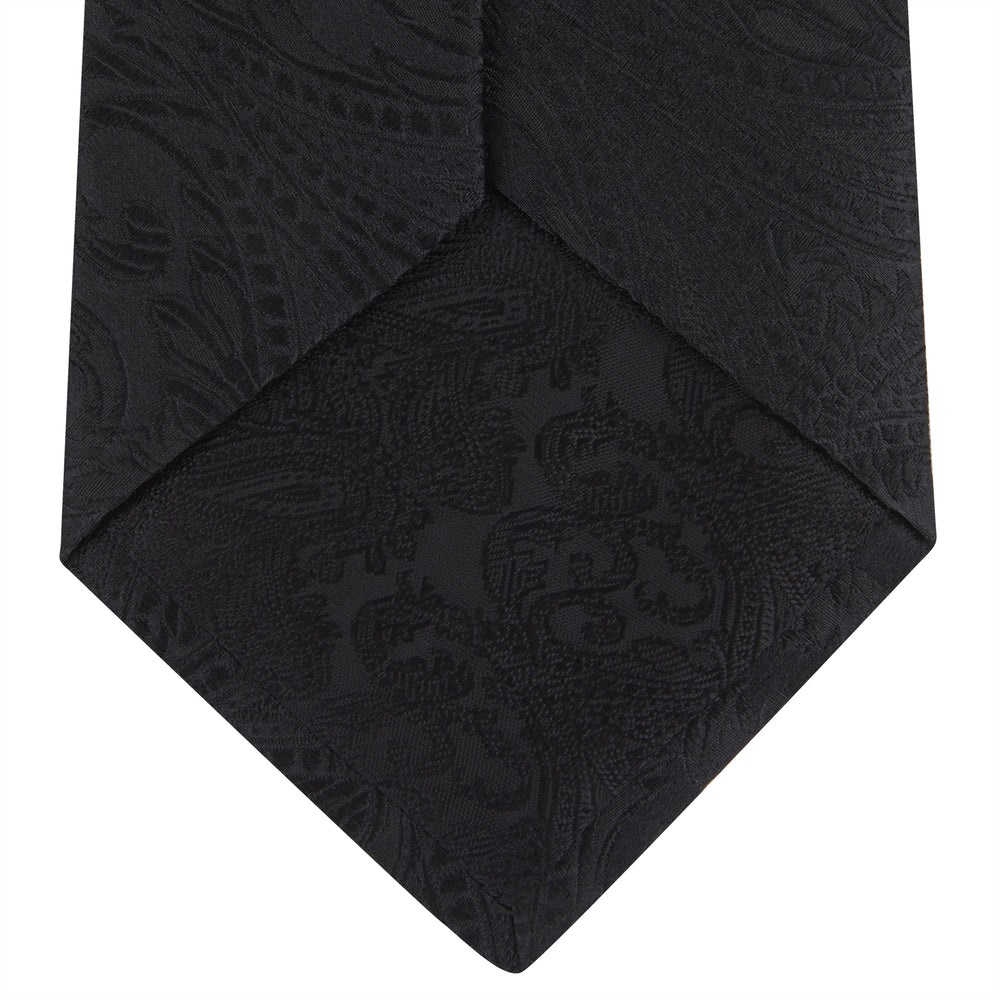 The Black Paisley Silk Tie by Turnbull & Asser features an elegant swirling paisley design with a subtle sheen—an all-black statement accessory photographed rolled up on a white background.