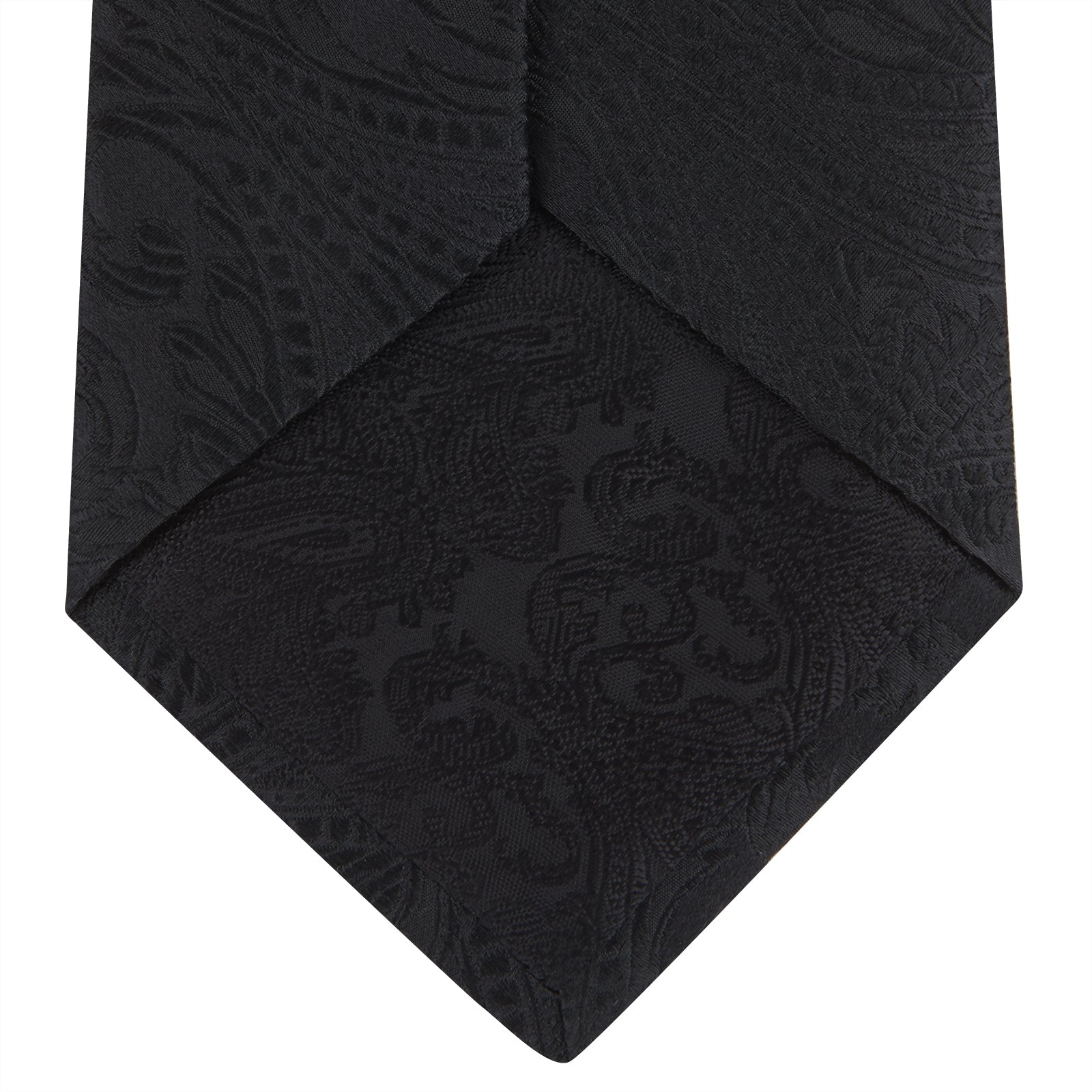 View 4 of product The Black Paisley Silk Tie by Turnbull & Asser features an elegant swirling paisley design with a subtle sheen—an all-black statement accessory photographed rolled up on a white background.