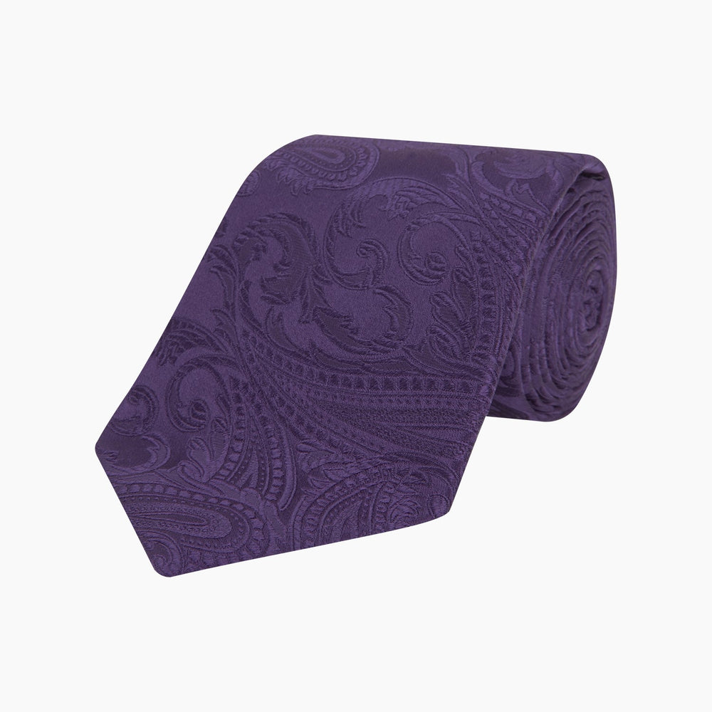 The Turnbull & Asser Purple Paisley Silk Tie, shown rolled on a white background, features an elegant paisley design—a stylish statement piece for any occasion.