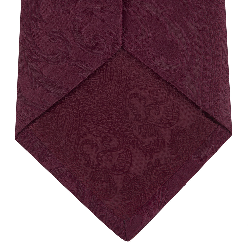 The Turnbull & Asser Burgundy Paisley Silk Tie, showcased rolled on a white background, is an elegant statement piece featuring a refined paisley design for any wardrobe.