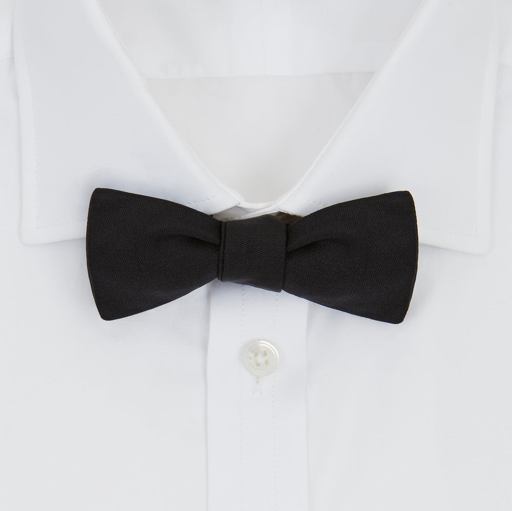 The Black Narrow Silk Bow Tie by Turnbull & Asser features a classic slim design with a matte finish, neatly tied and centered on a plain white background—perfect for formal occasions.