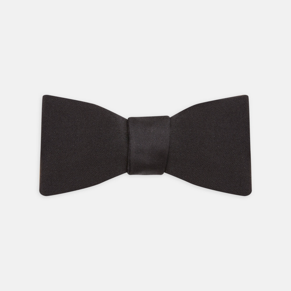 The Turnbull & Asser Black Silk Bow Tie features a matte finish and classic design, ideal for formal occasions. Shown pre-tied against a plain white background.