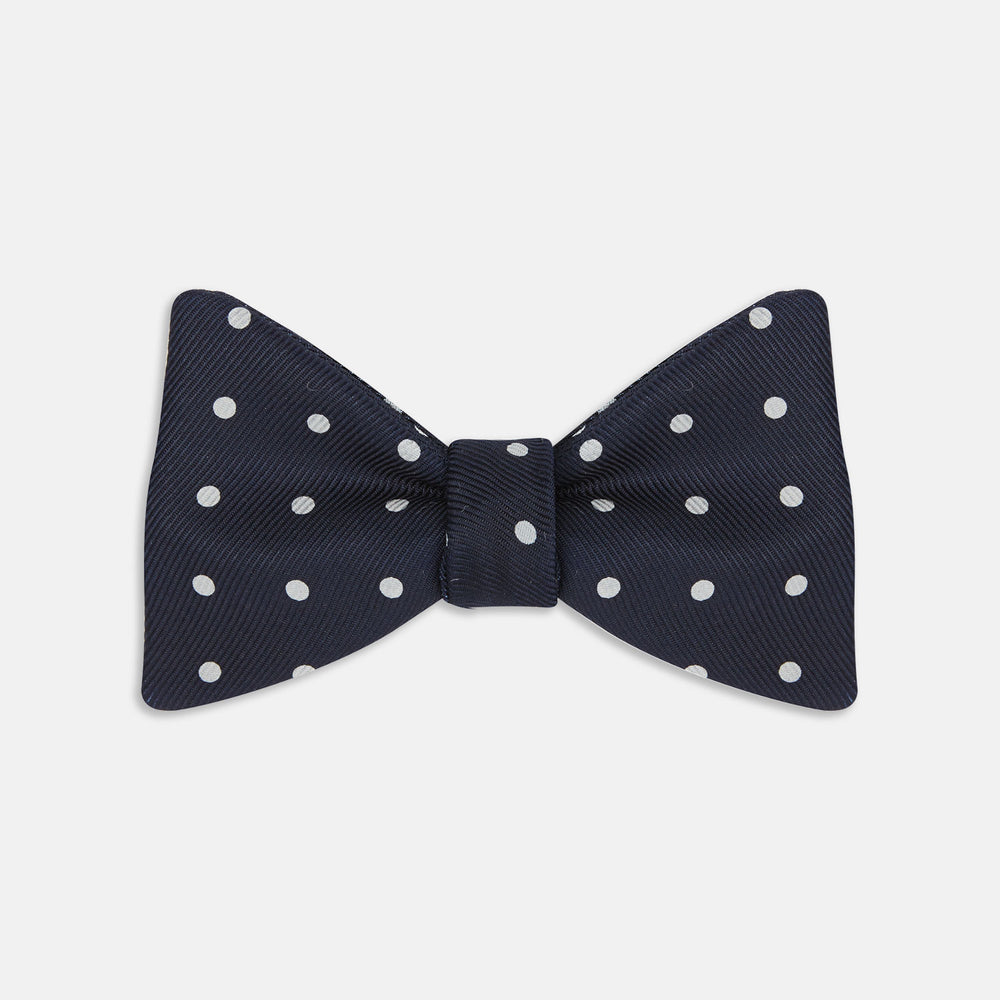 The Winston Navy and White Spot Silk Bow Tie by Turnbull & Asser features classic white polka dots on navy silk, reminiscent of Winston Churchill's style, and is shown against a plain white background.