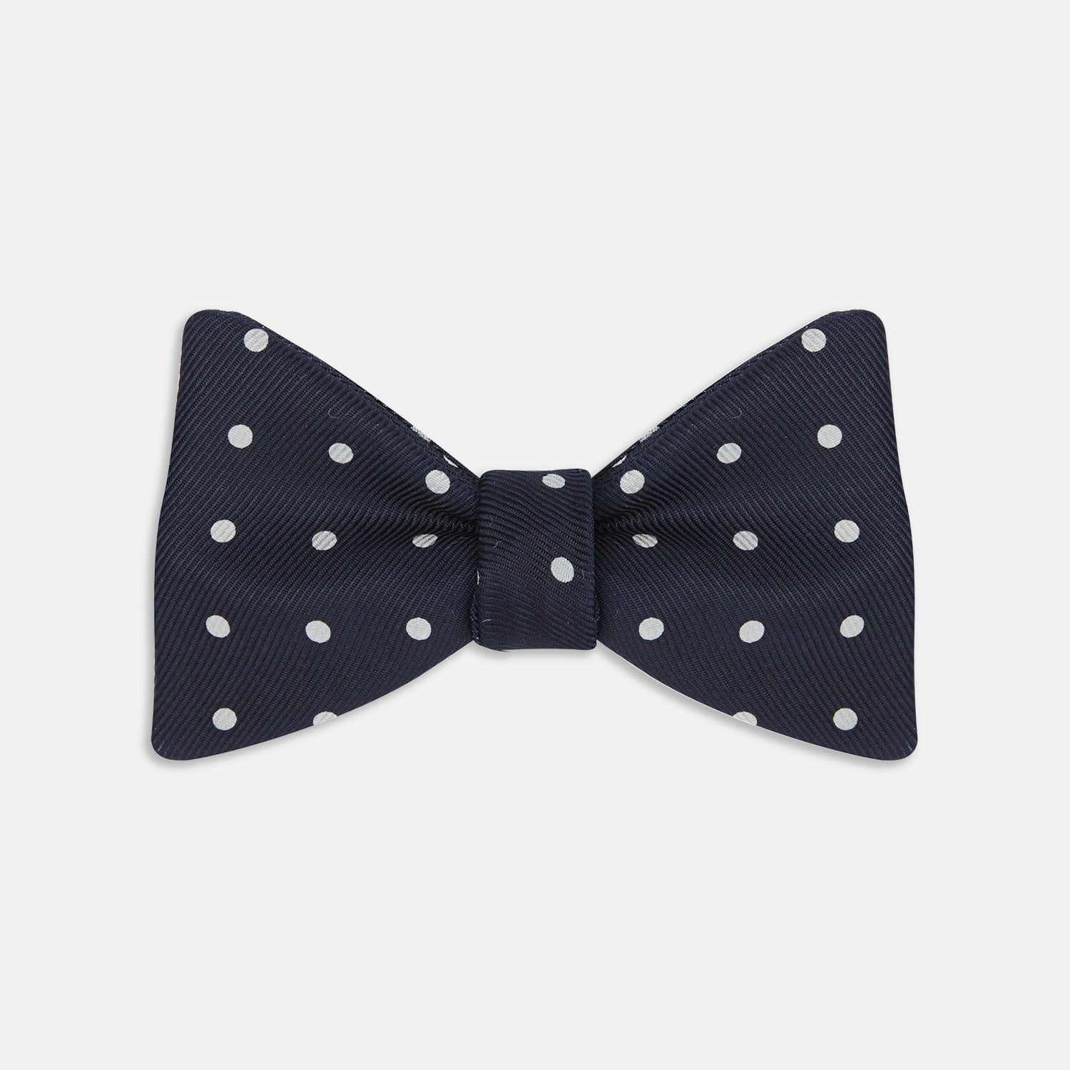 View 1 of product The Winston Navy and White Spot Silk Bow Tie by Turnbull & Asser features classic white polka dots on navy silk, reminiscent of Winston Churchill's style, and is shown against a plain white background.