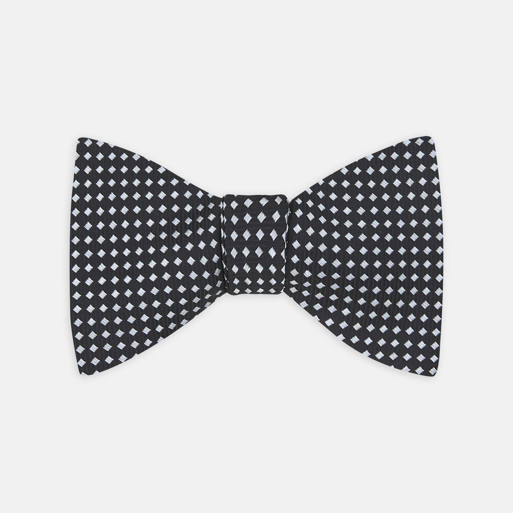 The Turnbull & Asser Diamond Black and White Silk Bow Tie features a black woven silk design with a tessellated diamond pattern of small white shapes, shown against a plain white background.
