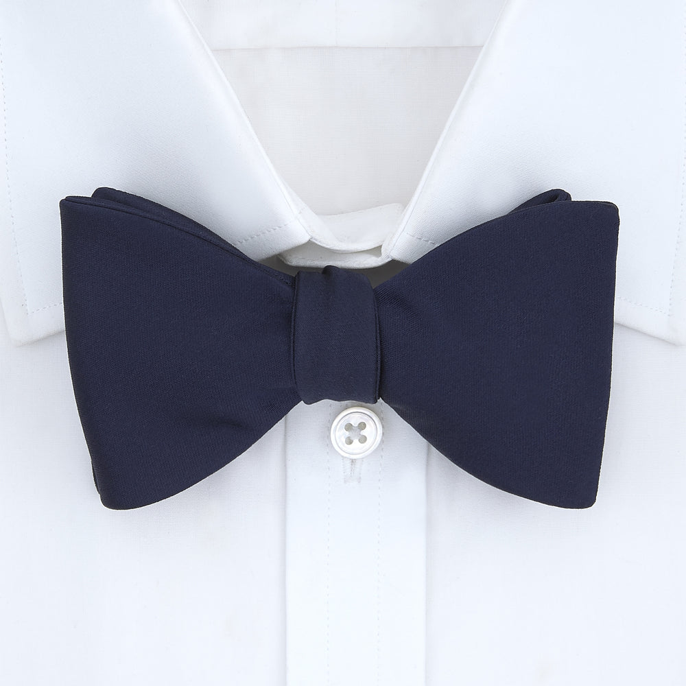 The Turnbull & Asser Navy Satin Silk Bow Tie is elegantly showcased against a plain white background.