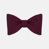View 1 of product The Turnbull & Asser Burgundy Barathea Bow Tie, shown neatly tied with pointed ends on a white background, features smooth matte fabric for a refined formal look.