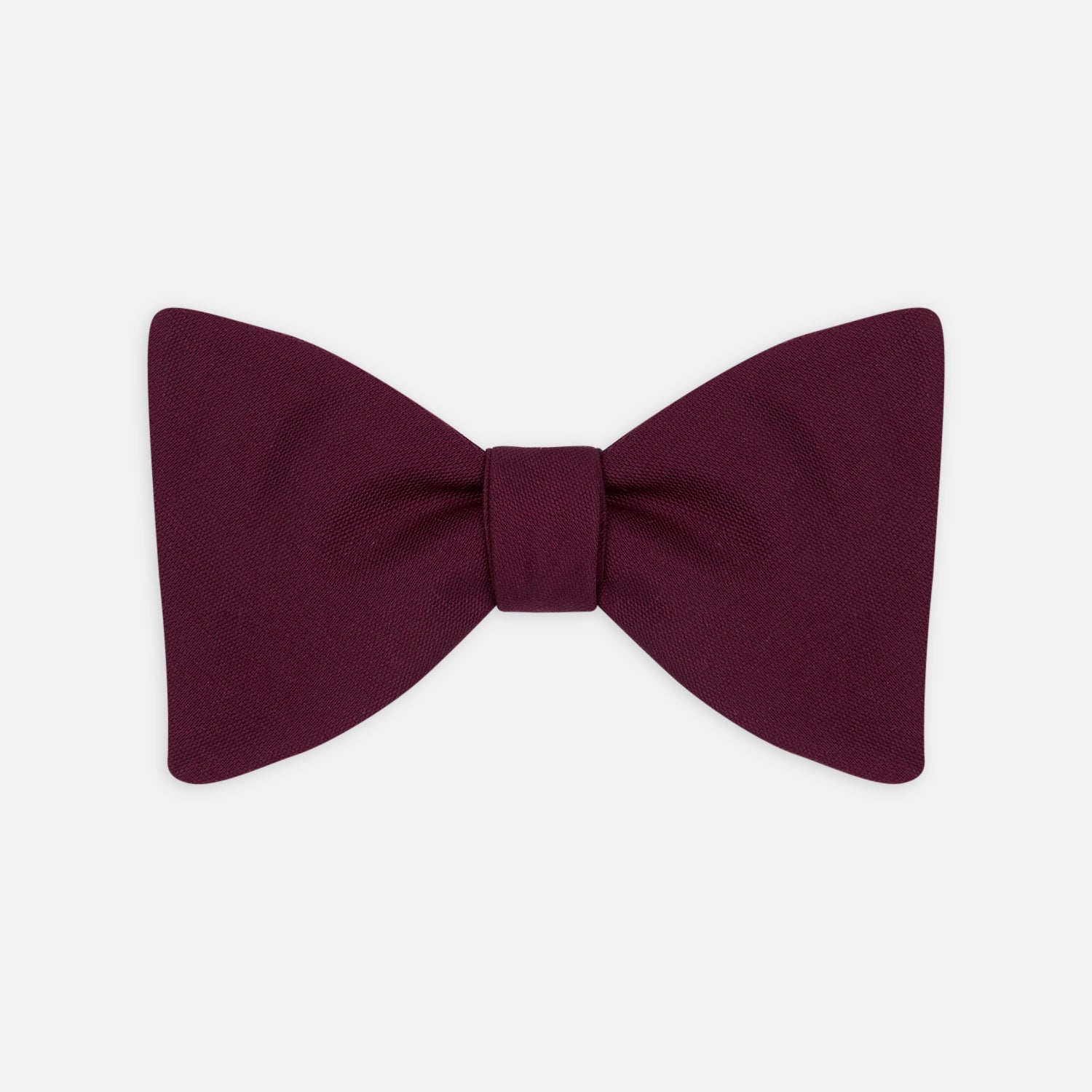 View 1 of product The Turnbull & Asser Burgundy Barathea Bow Tie, shown neatly tied with pointed ends on a white background, features smooth matte fabric for a refined formal look.
