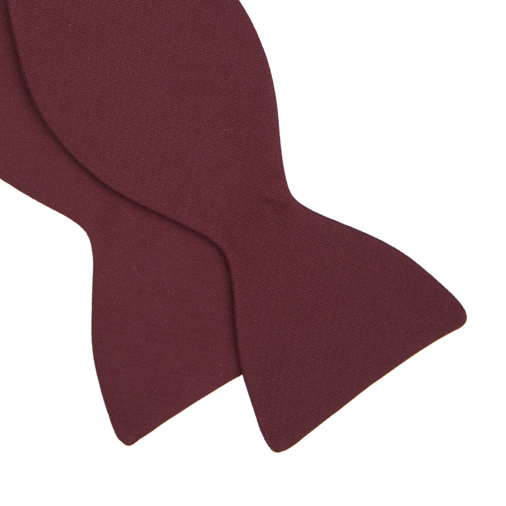 The Turnbull & Asser Burgundy Barathea Bow Tie, shown neatly tied with pointed ends on a white background, features smooth matte fabric for a refined formal look.