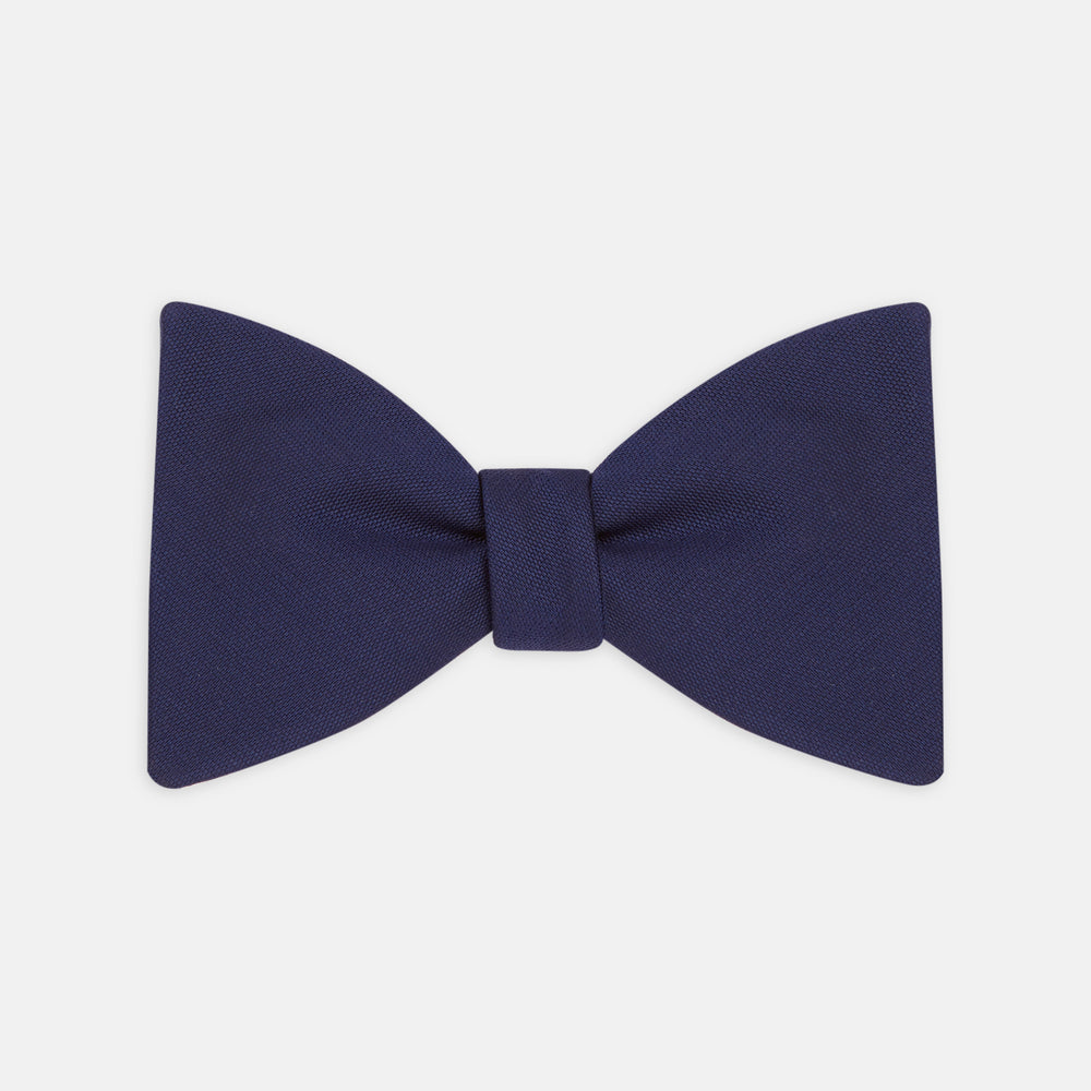 The Turnbull & Asser Navy Barathea Bow Tie features a classic butterfly shape in deep blue silk, ideal for formal occasions, shown against a white background.