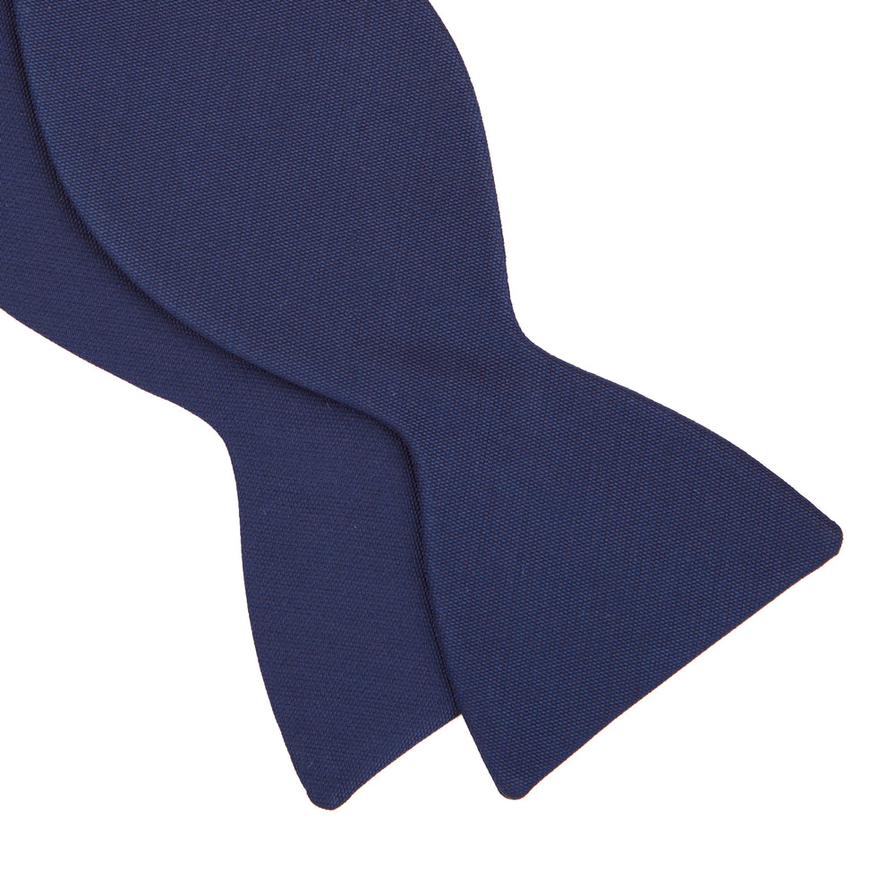 The Turnbull & Asser Navy Barathea Bow Tie features a classic butterfly shape in deep blue silk, ideal for formal occasions, shown against a white background.
