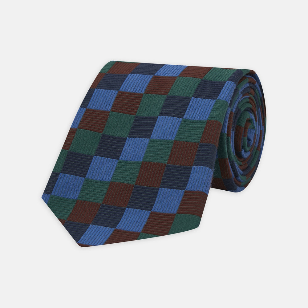 The Turnbull & Asser Navy and Blue Checkerboard Jacquard Wool Tie showcases a stylish checkered pattern, ideal for adding refined autumn tones to your ensemble.