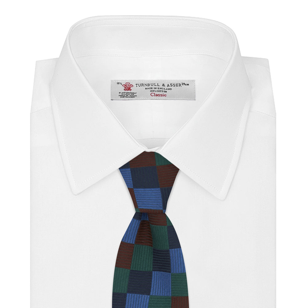 The Turnbull & Asser Navy and Blue Checkerboard Jacquard Wool Tie showcases a stylish checkered pattern, ideal for adding refined autumn tones to your ensemble.