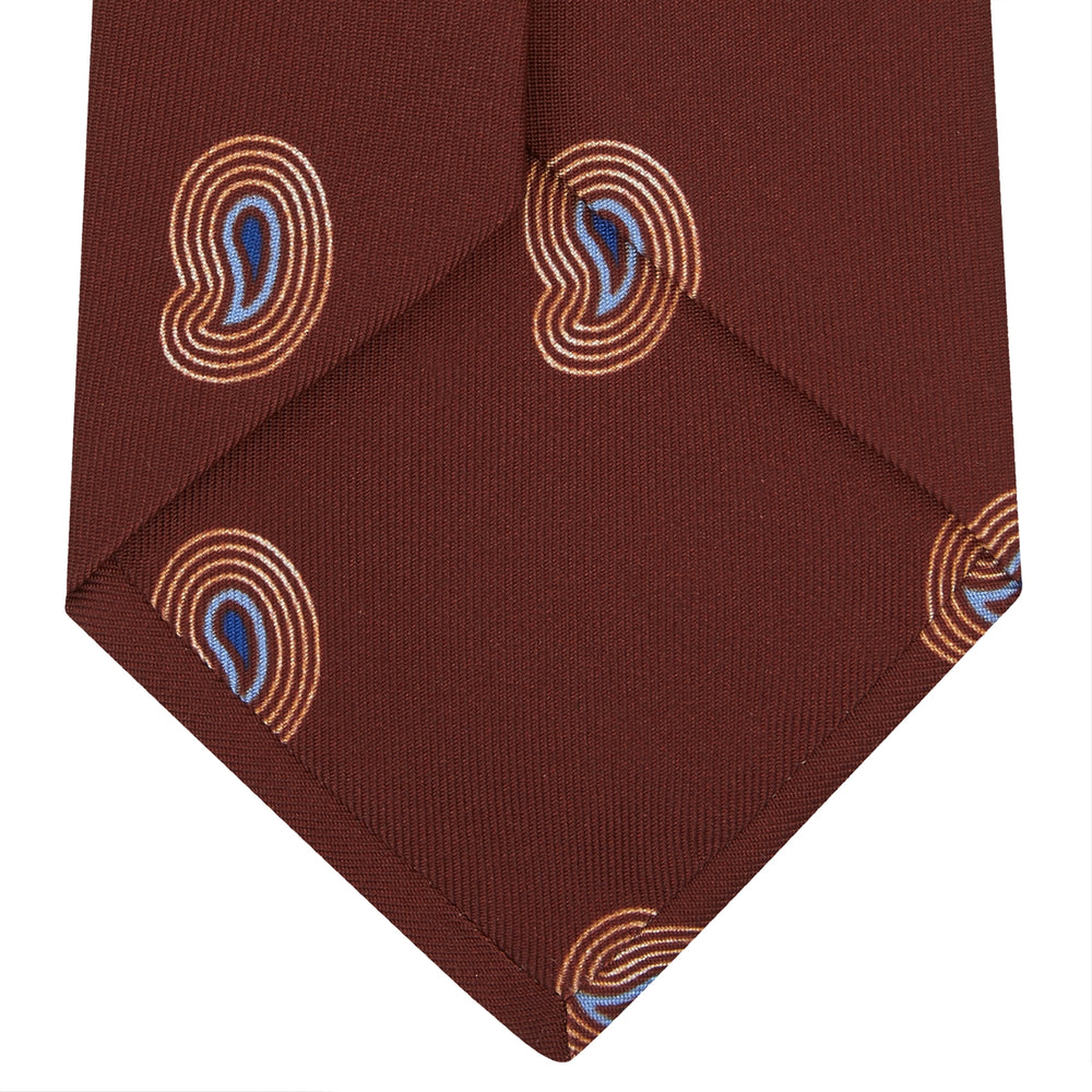 The Turnbull & Asser Red Pulse Paisley Silk Tie features a rolled red silk design with a repeating pattern of tan, blue, and white abstract pulse motifs.
