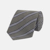 View 1 of product The Turnbull & Asser Grey Diagonal Stripe Cotton and Silk Tie features a navy, grey, and white striped pattern and is shown rolled up against a plain white background.