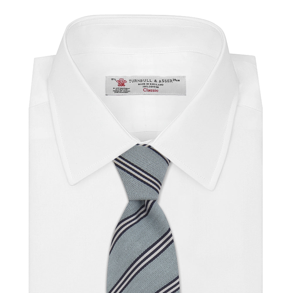 The Turnbull & Asser Powder Blue Diagonal Stripe Cotton and Silk Tie, featuring navy and white club stripes, is shown rolled up on a plain white background.