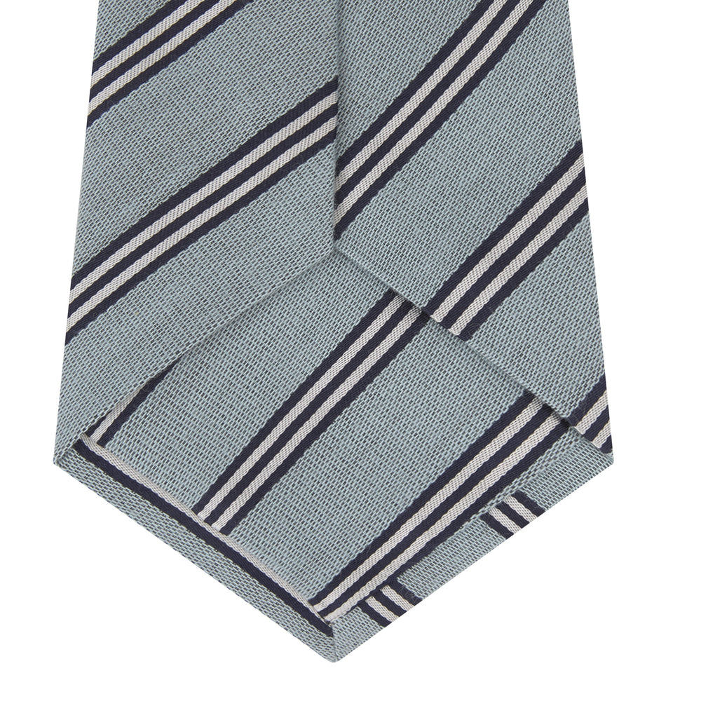 The Turnbull & Asser Powder Blue Diagonal Stripe Cotton and Silk Tie, featuring navy and white club stripes, is shown rolled up on a plain white background.