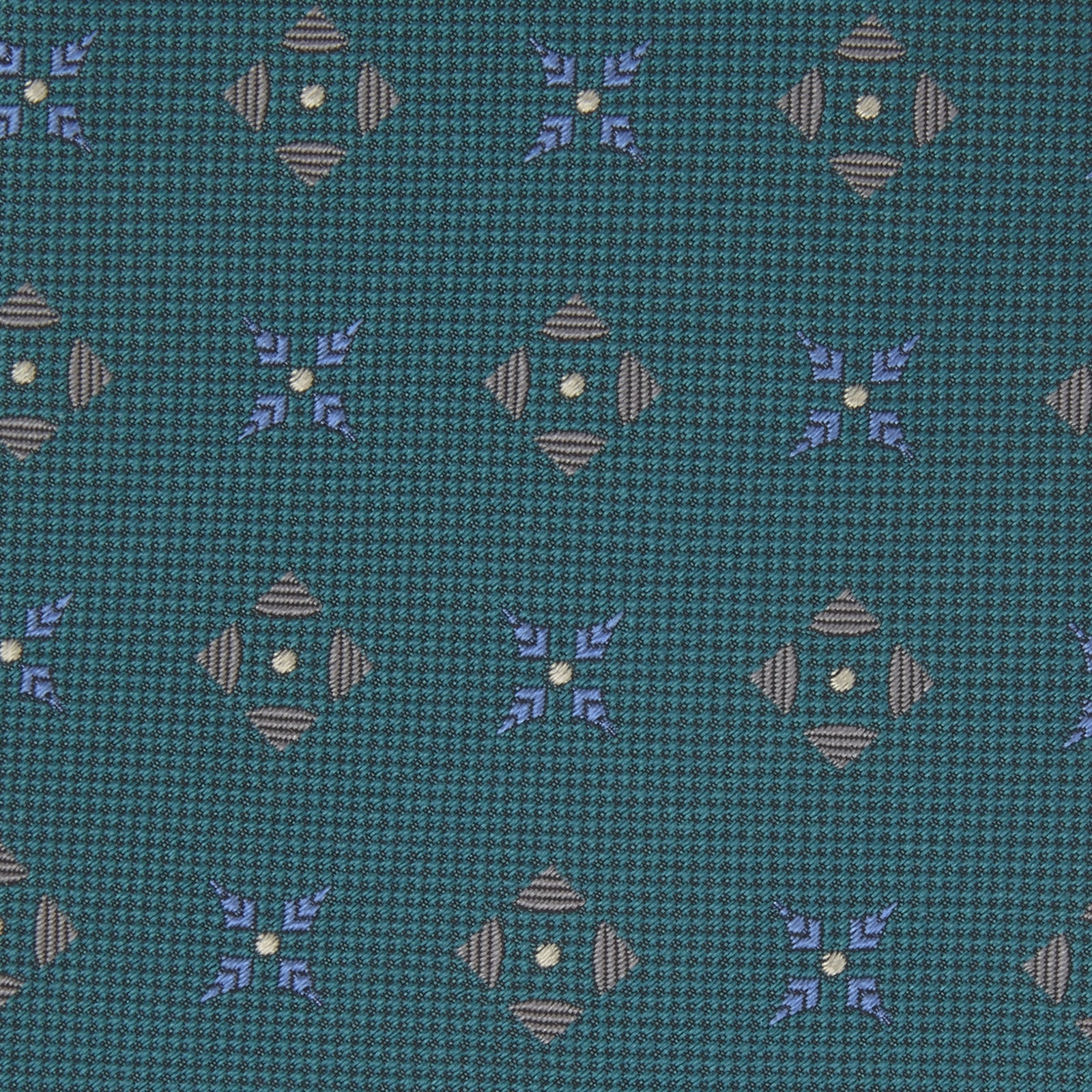 View 3 of product The Turquoise Crosses Silk Tie by Turnbull & Asser features a subtle geometric motif in tan and blue, displayed rolled on a white background—ideal for the modern office.