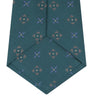 View 4 of product The Turquoise Crosses Silk Tie by Turnbull & Asser features a subtle geometric motif in tan and blue, displayed rolled on a white background—ideal for the modern office.