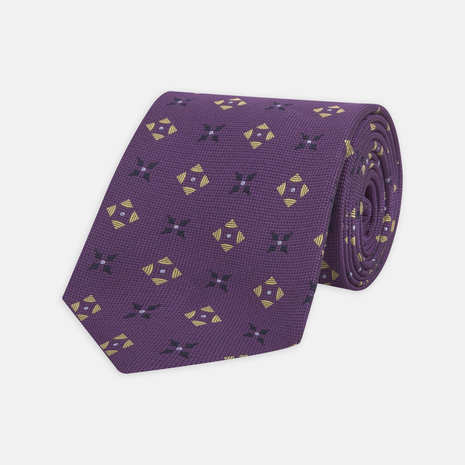 View 1 of product The Turnbull & Asser Purple Crosses Silk Tie features a rolled-up purple design with small yellow and black cross motifs on silk.