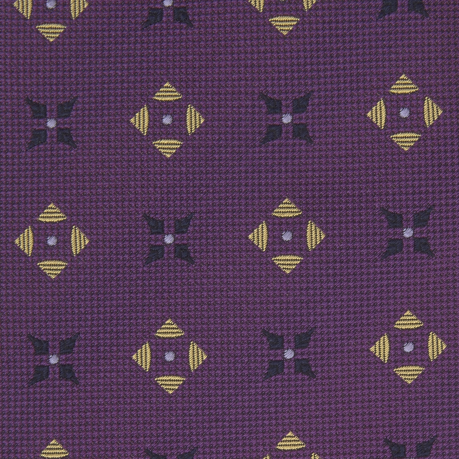 View 3 of product The Turnbull & Asser Purple Crosses Silk Tie features a rolled-up purple design with small yellow and black cross motifs on silk.