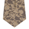View 4 of product The Copper Floral Occasion Silk Tie by Turnbull & Asser features a gold floral jacquard pattern on brown silk, elegantly rolled on a white surface—an ideal choice for weddings.