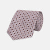View 1 of product The Turnbull & Asser Pastel Pink Geometric Silk Tie features a small, repeating dark brown and white pattern for a mid-century look—ideal with tailored jackets. Shown rolled up on a white background.