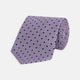 The Turnbull & Asser Lilac Geometric Silk Tie features a small, repeating mid-century motif in dark purple and black on white—an ideal accent for tailored jackets.