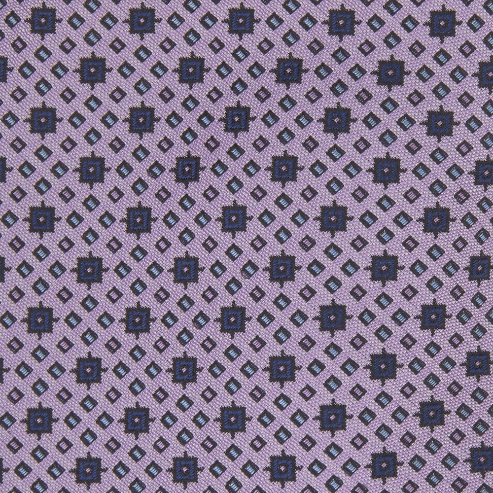 The Turnbull & Asser Lilac Geometric Silk Tie features a small, repeating mid-century motif in dark purple and black on white—an ideal accent for tailored jackets.