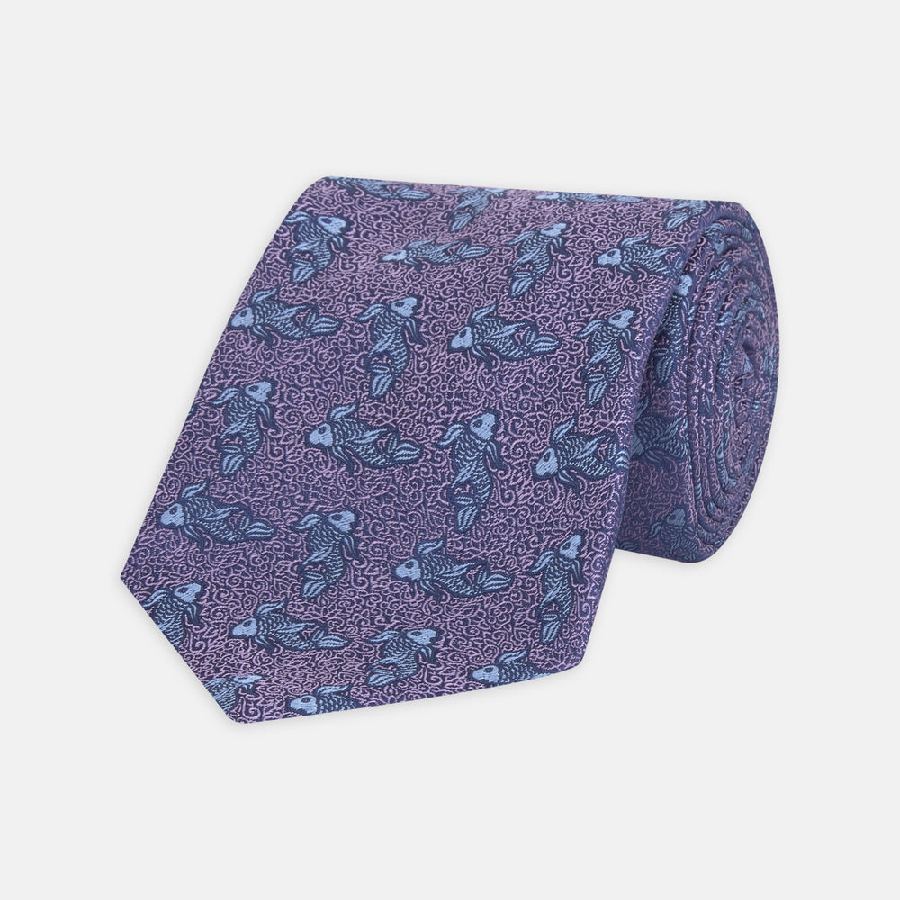 The Turnbull & Asser Purple Carp Silk Tie, woven in England, features blue koi fish and swirling patterns on purple silk and is shown against a plain white background.