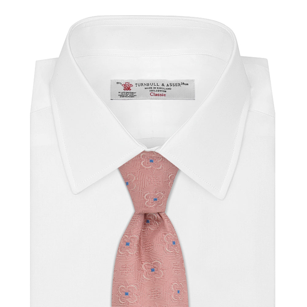 The Pink Flower Mosaic Silk Tie by Turnbull & Asser features a subtle jacquard texture with small blue floral accents, shown on a white background.