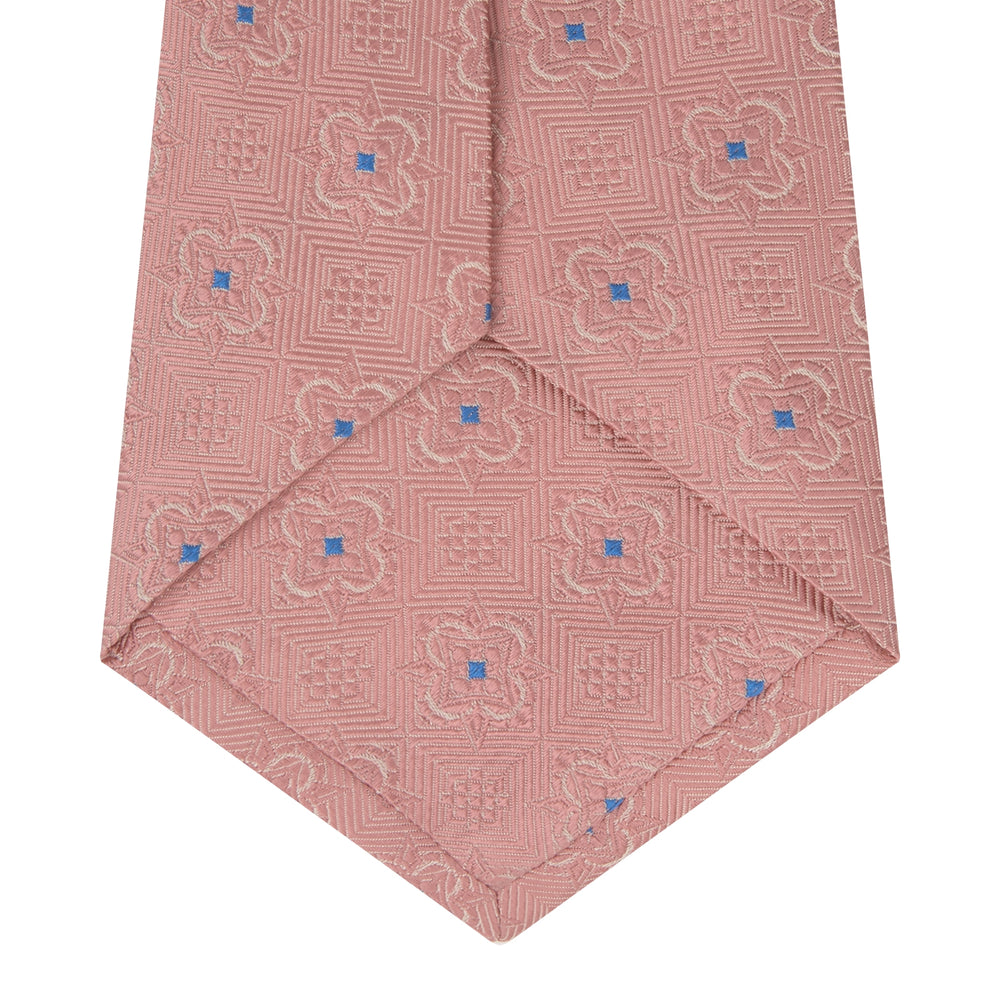The Pink Flower Mosaic Silk Tie by Turnbull & Asser features a subtle jacquard texture with small blue floral accents, shown on a white background.