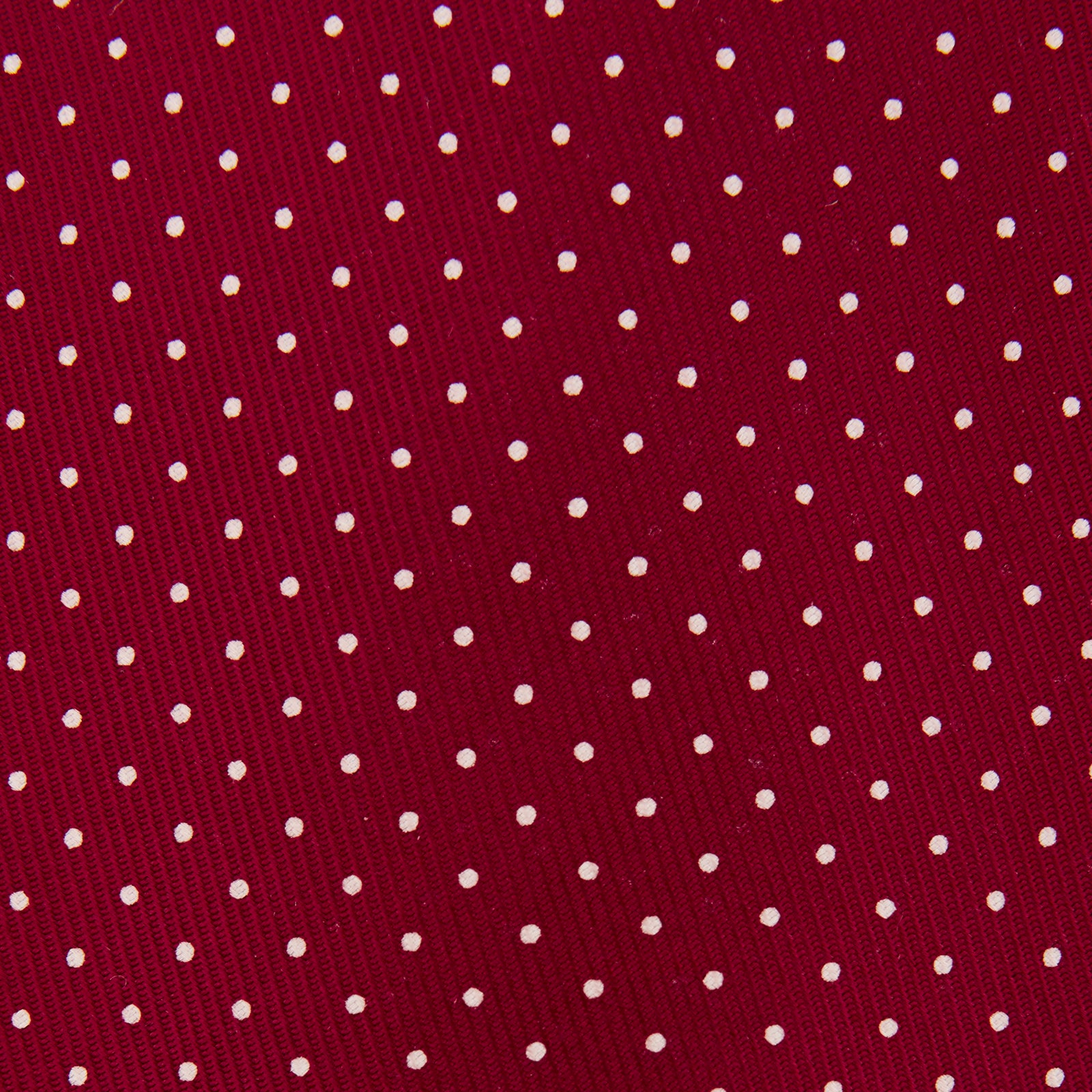 View 3 of product The Turnbull & Asser Burgundy and White Small Spot Printed Silk Tie, shown rolled against a plain white background, is an elegant accessory ideal for the office.