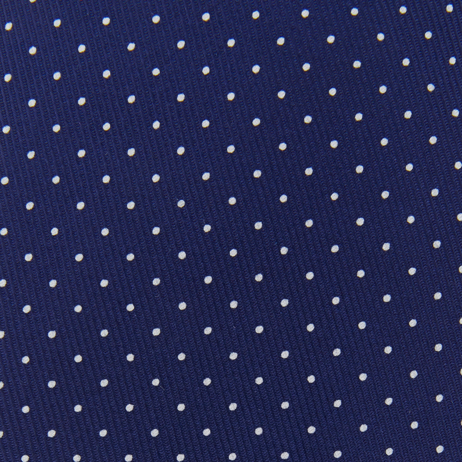 View 3 of product The Blue and White Small Spot Printed Silk Tie by Turnbull & Asser, shown rolled on a white background, features a refined white polka dot pattern—ideal for complementing any office shirt.