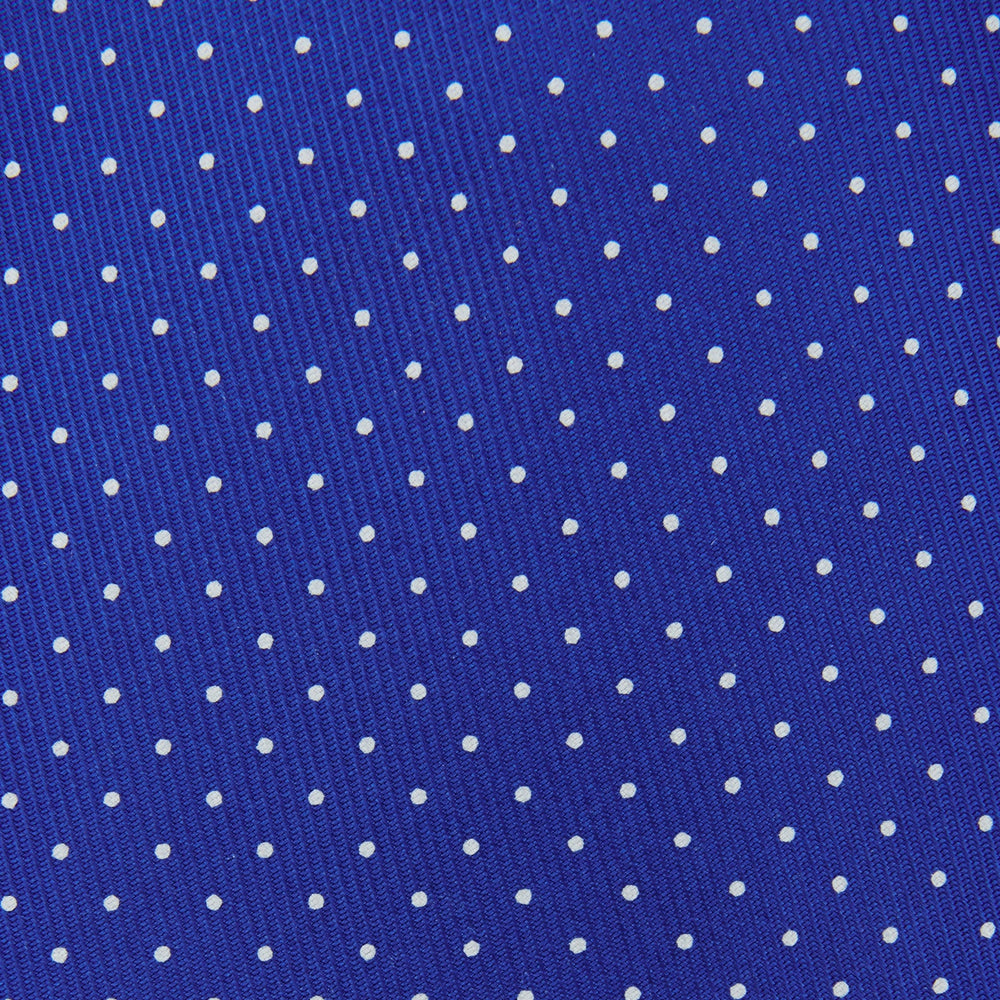 The Turnbull & Asser Slim Royal Blue and White Small Spot Printed Silk Tie, featuring white polka dots, is ideal for office wear and shown rolled up on a plain white background.