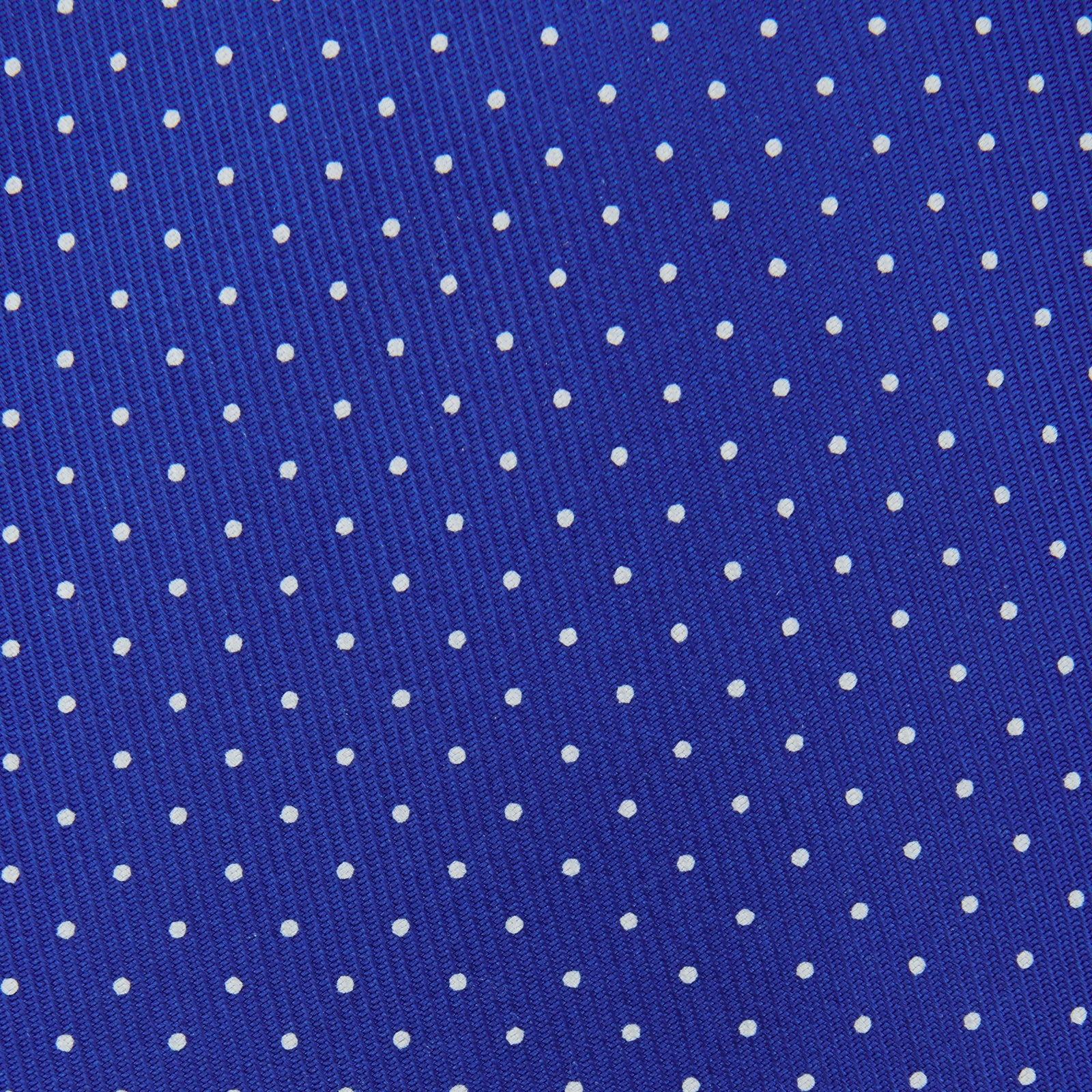 View 3 of product The Turnbull & Asser Slim Royal Blue and White Small Spot Printed Silk Tie, featuring white polka dots, is ideal for office wear and shown rolled up on a plain white background.