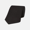 View 1 of product The Turnbull & Asser Long Black Grenadine Silk Tie features a subtle woven pattern and knitted appearance, shown rolled at one end against a plain white background.
