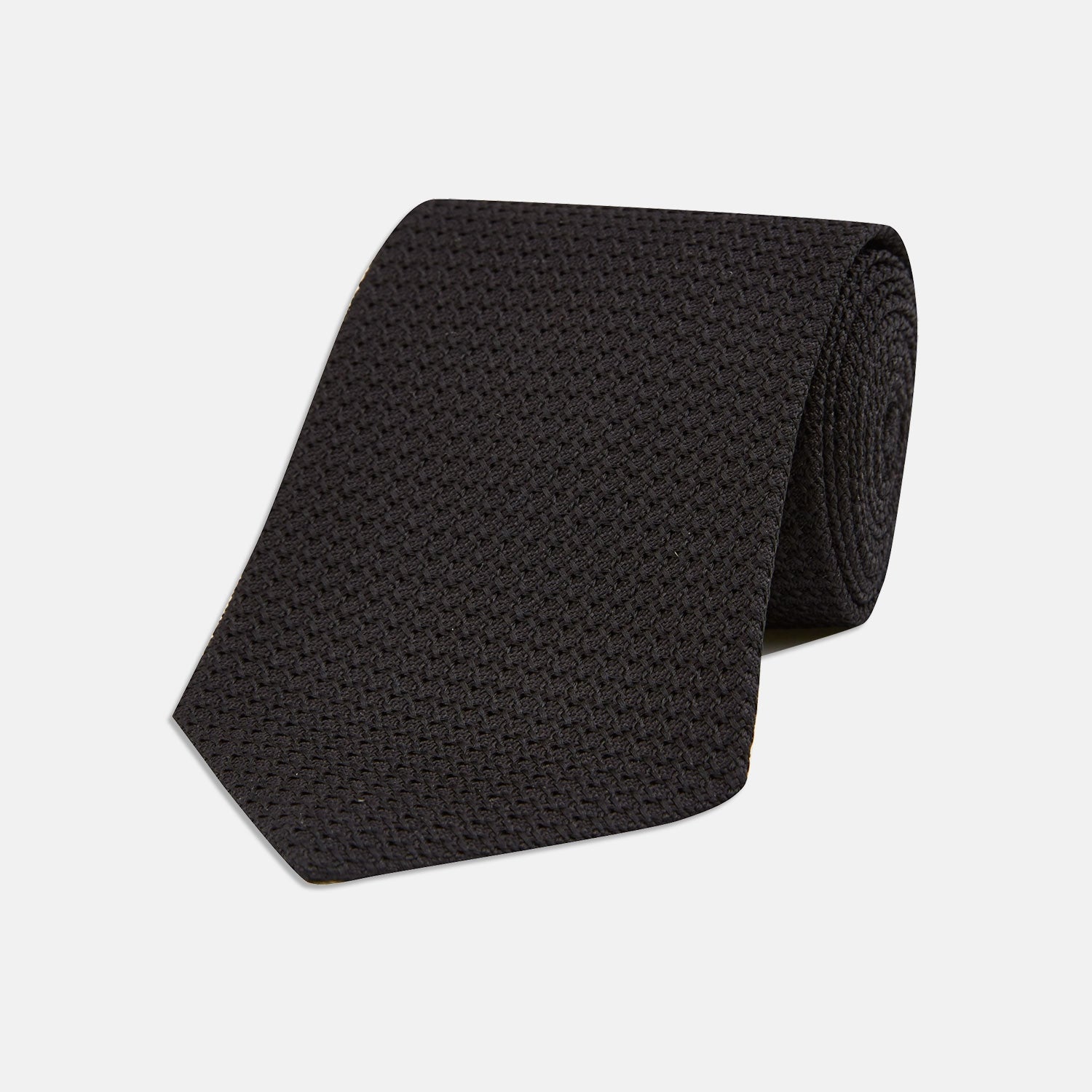 View 1 of product The Turnbull & Asser Long Black Grenadine Silk Tie features a subtle woven pattern and knitted appearance, shown rolled at one end against a plain white background.