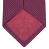View 4 of product The Turnbull & Asser Wine Grenadine Silk Tie, featuring a textured weave in dark purple, is displayed rolled-up on a plain white background.