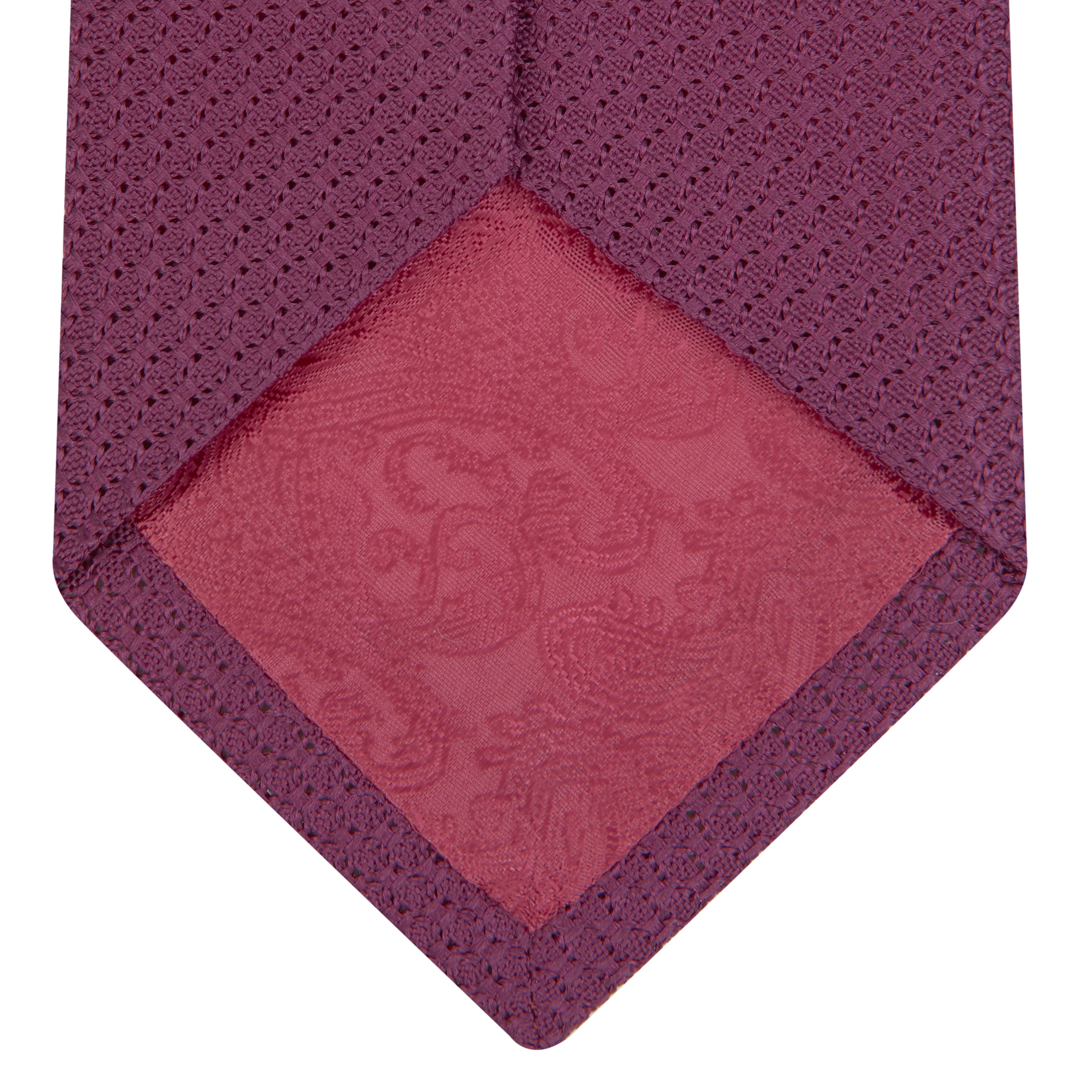 View 4 of product The Turnbull & Asser Wine Grenadine Silk Tie, featuring a textured weave in dark purple, is displayed rolled-up on a plain white background.