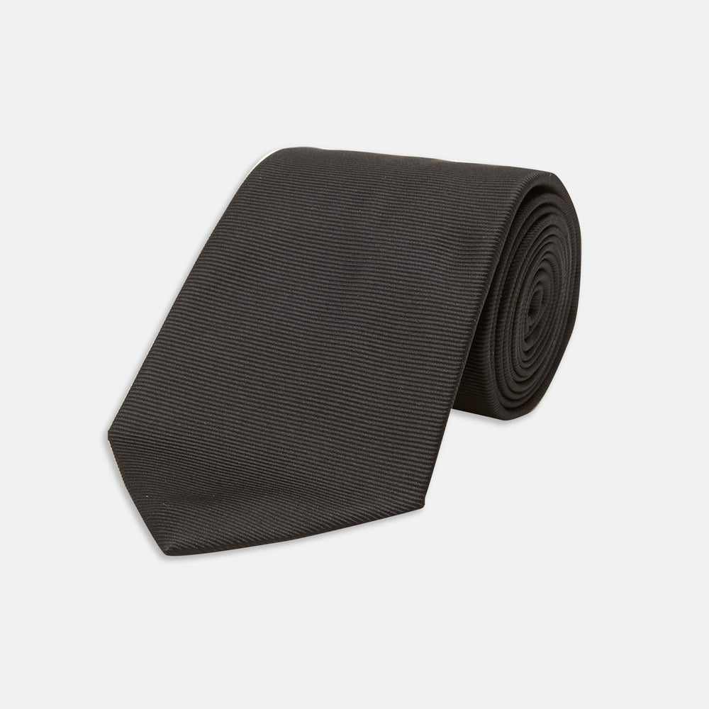 The Turnbull & Asser Black Twill Silk Tie features a subtle textured pattern and is displayed neatly rolled on a plain white background.