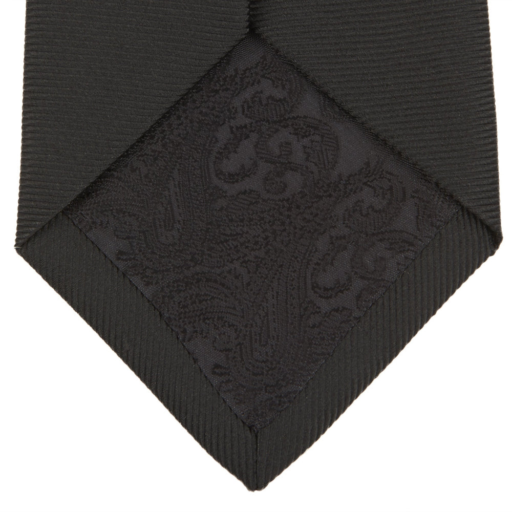 The Turnbull & Asser Slim Black Twill Silk Tie is neatly rolled on a white background, offering an ideal smart finish when paired with cotton shirts.