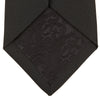 View 4 of product The Turnbull & Asser Black Twill Silk Tie features a subtle textured pattern and is displayed neatly rolled on a plain white background.