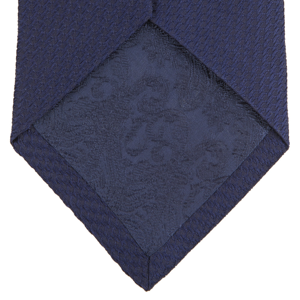 A close-up of the Turnbull & Asser Long Navy Lace Silk Tie, featuring a subtle lace weave texture, rolled up and displayed on a plain white background.